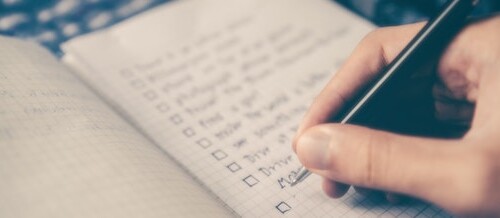 hand with pen writing list in notebook